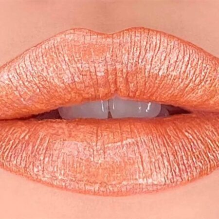 תקריב של שפתיים המרוחות בשפתון מטאלי עמיד בגוון 66, שפתון בצבע אפרסק-כתום מטאלי בעל גימור מבריק ומחזיר אור. השפתיים פתוחות קלות וחושפות שיניים לבנות. הרקע בצבע עור. | אלמאס קוסמטיקה – מתנה מושלמת של טיפוח ויוקרה