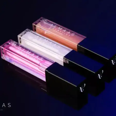 שלושה שפופרות מלבניות עם הכיתוב "ערכה לעיבוי שפתיים - מהדורה מוגבלת" ומכסים שחורים, בגווני ורוד, שקוף וניוד, מסודרות באלכסון על רקע כהה. התמונה המבריקה משדרת תחושה יוקרתית. | אלמאס קוסמטיקה – מתנה מושלמת של טיפוח ויוקרה