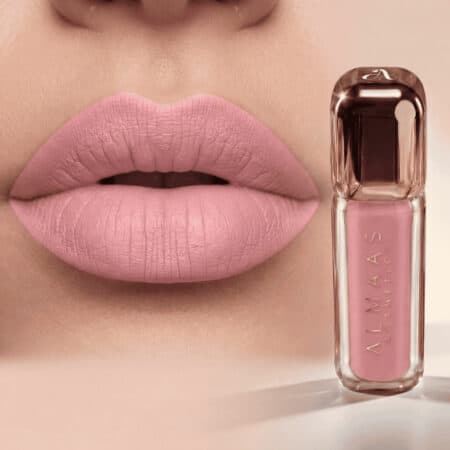 תקריב של שפתי אישה המורחות שפתון ורוד מט. לצד השפתיים מונח שפופרת שקופה של שפתון נוזלי ורוד, שעליה הכיתוב "ALLMAAS Cosmetics". הרקע ניטרלי, כך שהדגש נשאר על צבע השפתיים הוורוד העדין ועל מוצר הקוסמטיקה התואם. | אלמאס קוסמטיקה – מתנה מושלמת של טיפוח ויוקרה